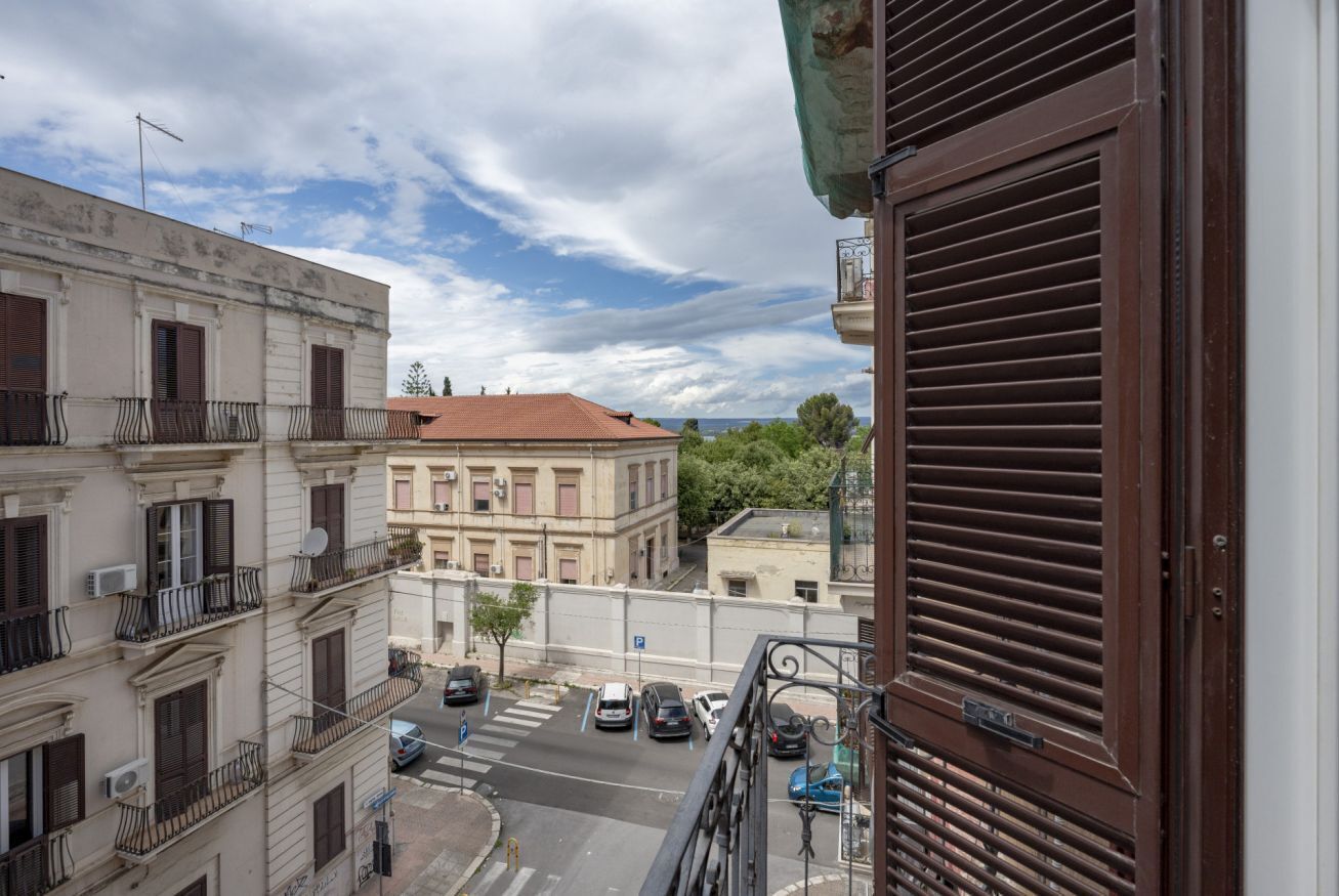 A street view with buildings, a clear sky, and parked cars.