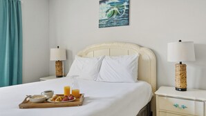 Habitación de hotel con cama, mesitas de noche, una bandeja de desayuno y un cuadro en la pared.