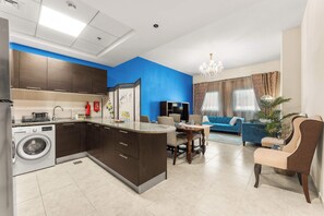 Eine moderne Küche mit integriertem Waschmaschine, ein Essbereich mit Tisch und Stühlen sowie ein Wohnzimmer mit Sofa und einer Deckenleuchte.