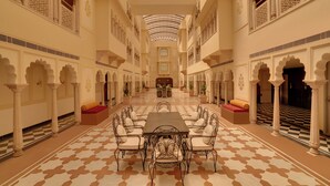 Un vaste hall doté d’une table centrale, de colonnes richement décorées et d’un sol à motifs.