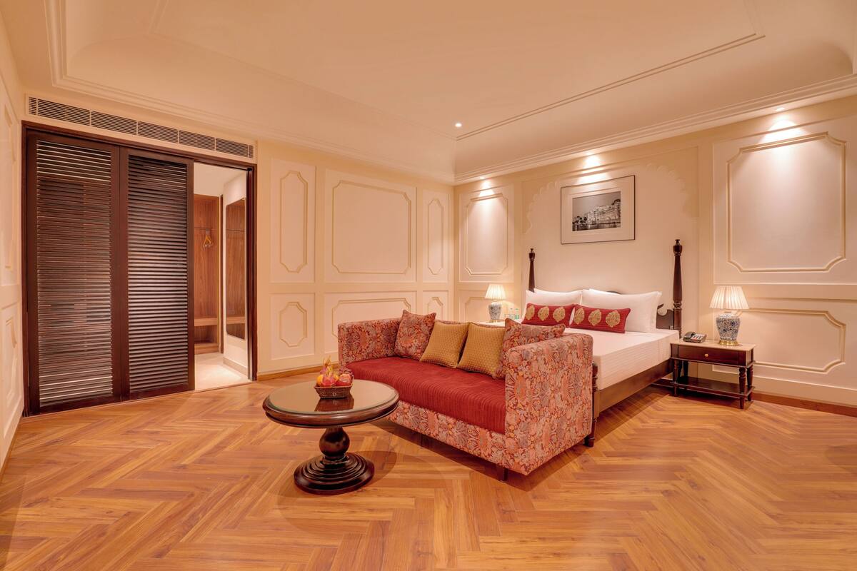 Quarto com sofá, mesa redonda, cama, mesa de cabeceira e guarda-roupa.