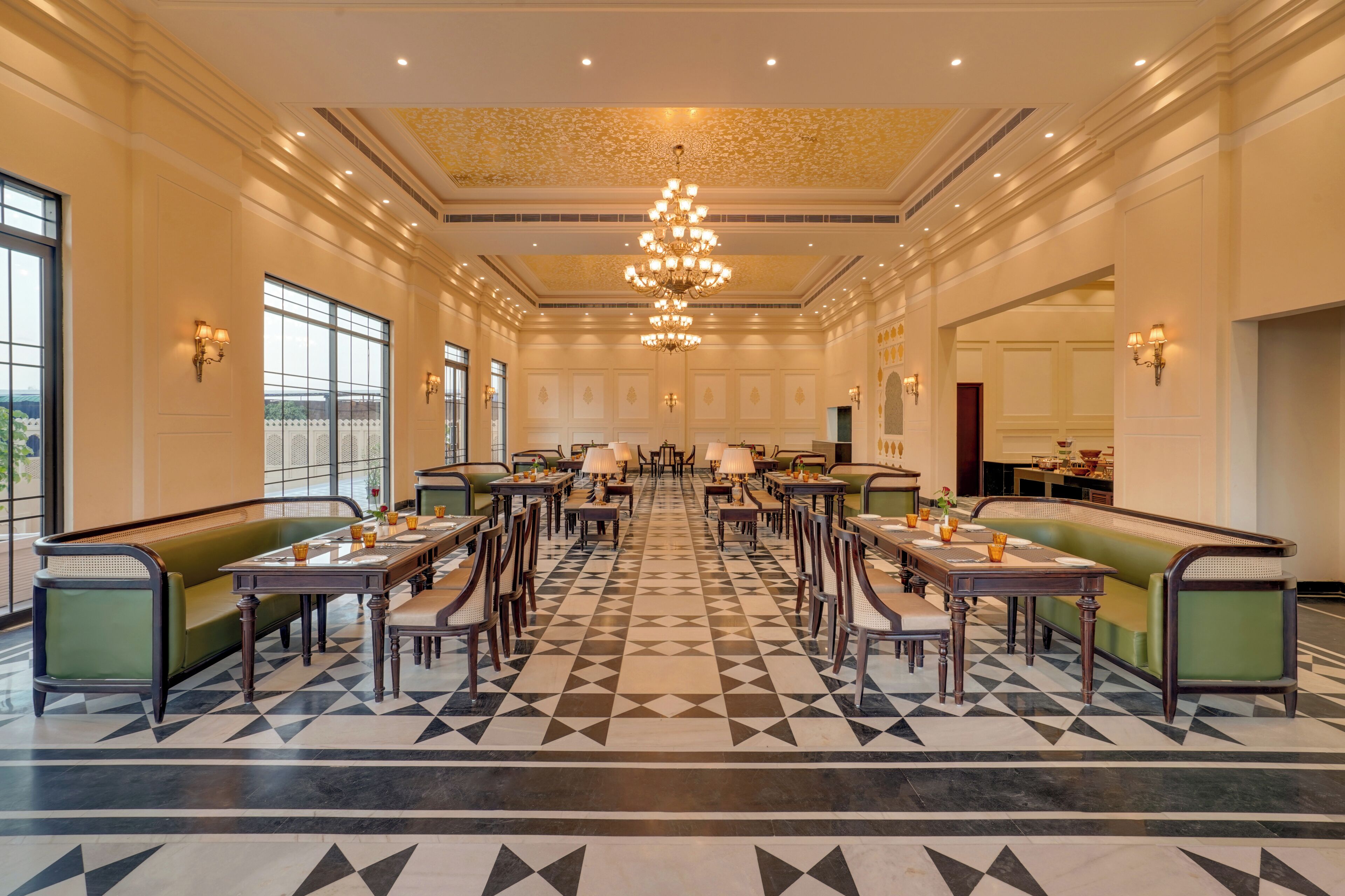 A spacious dining area with high ceilings, chandeliers, and a geometric patterned floor.