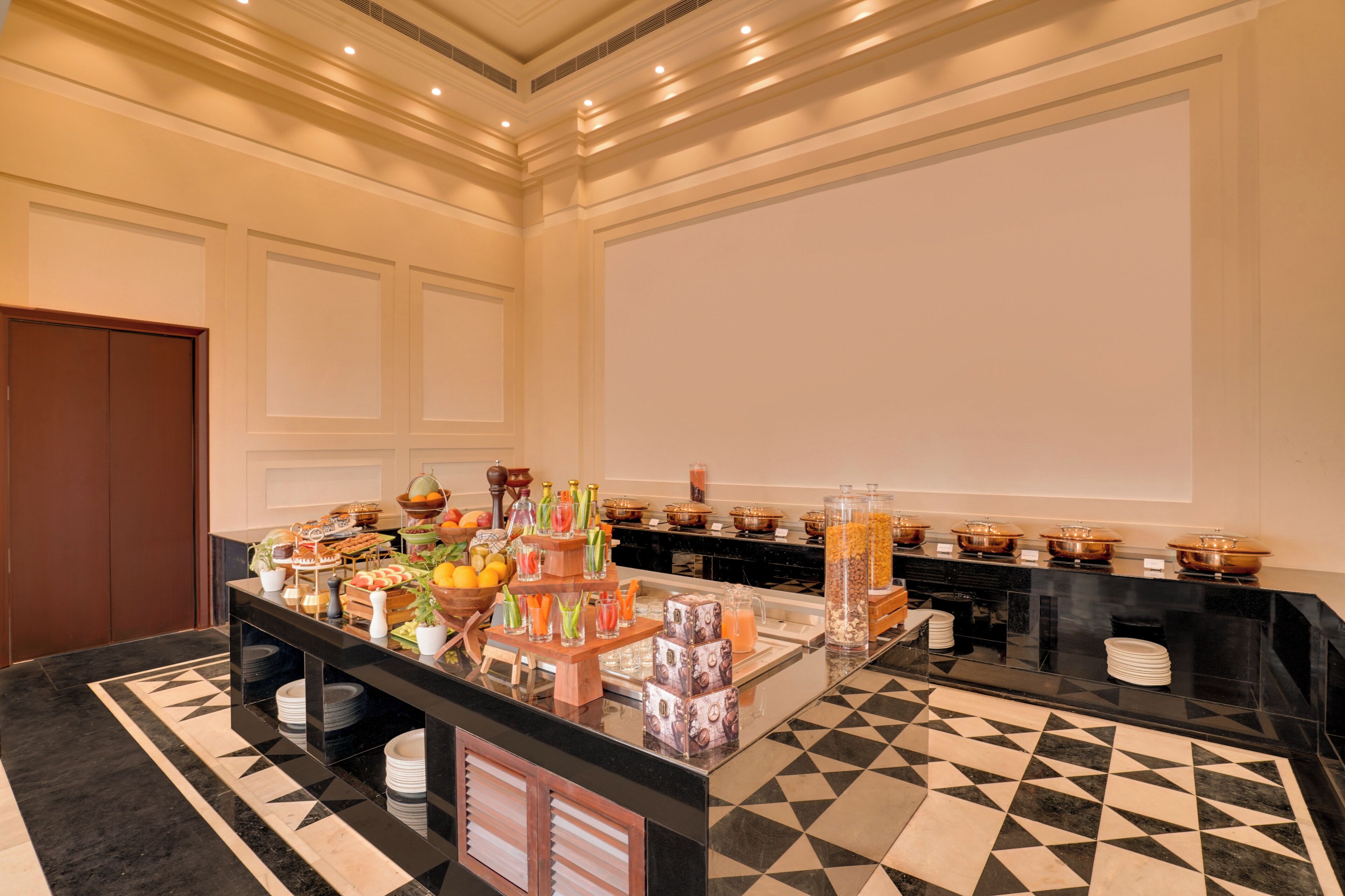 Ein Buffet mit verschiedenen Speisen, einem großen Bildschirm und einem gemusterten Boden.