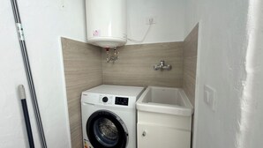 A compact laundry room with a washing machine, a sink, and a water heater. - Sunny Sea View Puerto Rico by Alquiler de Sueño (Mogan)