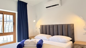 A hotel room with a bed, a window with curtains, an air conditioning unit, and a wall-mounted light. - Sunny Sea View Puerto Rico by Alquiler de Sueno (Mogan)