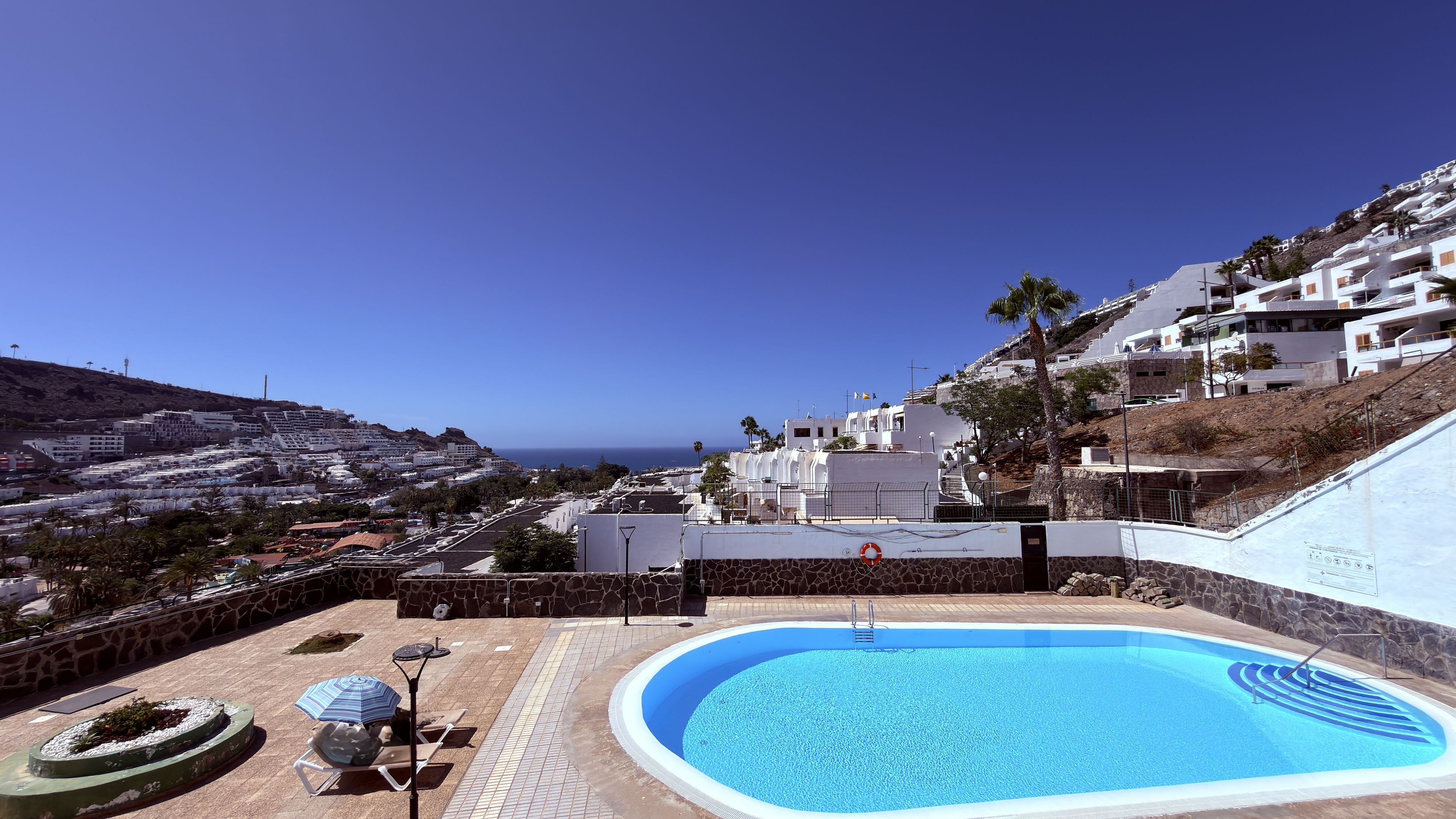 Piscina com vista para uma cidade costeira e céu claro.