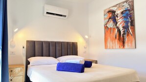 A bedroom with a bed, pillows, a wall-mounted air conditioner, a painting, and a bedside table. - Sunny Sea View Puerto Rico by Alquiler de Sueño (Mogan)
