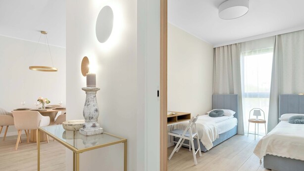 Een moderne hotelkamer met een glazen tafel, een bed met hoofdeinde, een bureau en een stoel.