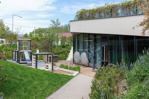 Ein modernes Gebäude mit großen Glasfenstern, einer Rutsche und Sitzgelegenheiten im Freien.