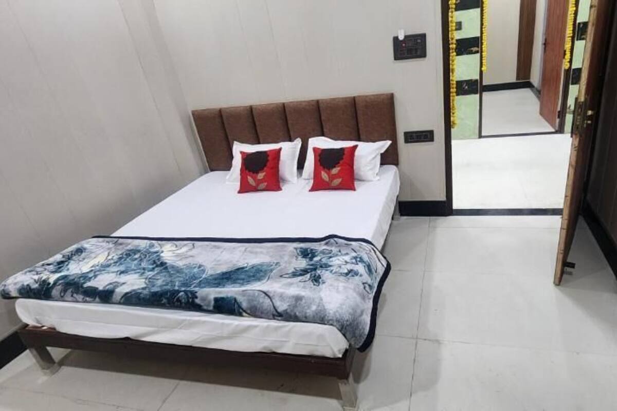 Quarto de hotel com cama, cabeceira e espelho refletindo o ambiente.