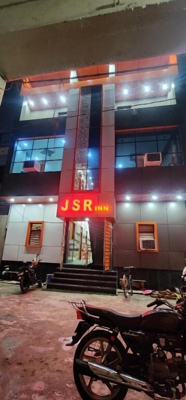 Un bâtiment sur lequel on peut voir une enseigne bien visible indiquant « JSR Inn », avec de nombreuses fenêtres et un escalier menant à l’entrée.