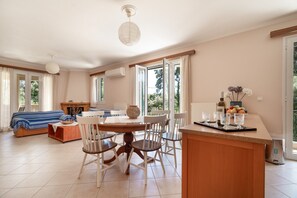 A spacious living area with a dining table, chairs, and a kitchen counter. - Jennifer's Apartments Lefkada – Comfortable Stay with City Views (Lefkada)