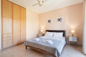 A bedroom with a bed, nightstands, a wardrobe, and ceiling fan. - Jennifer's Apartments Lefkada – Comfortable Stay with City Views (Lefkada)