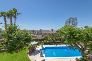 A swimming pool surrounded by lush greenery, a patio with outdoor furniture, and a view of a residential area. - Holiday Home 'Elegance, Privacy, and Comfort' with Sea View, Private Pool and Wi-Fi (Calafell)
