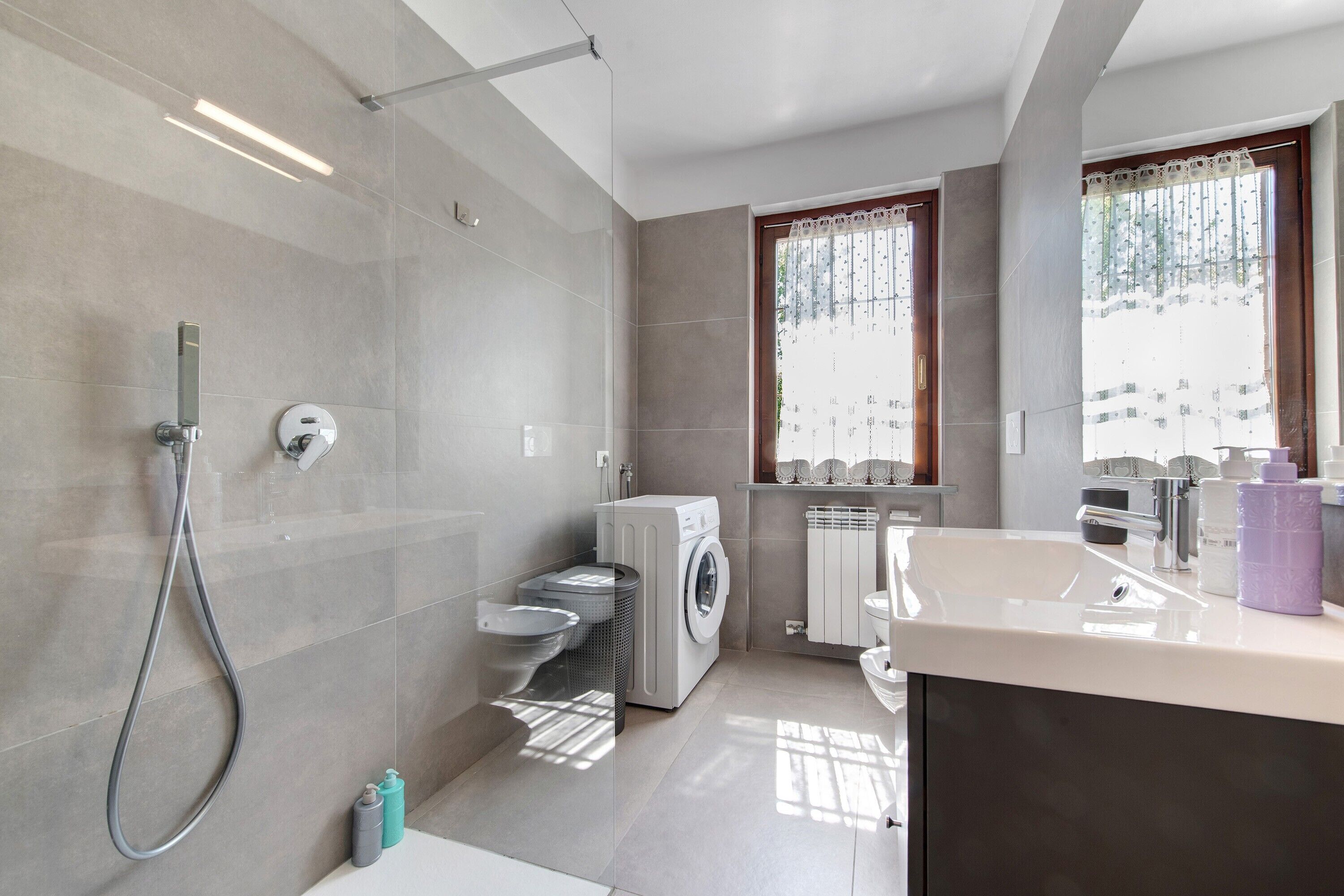 Une salle de bain moderne équipée d’une douche, de toilettes, d’un lave-linge et d’un lavabo.