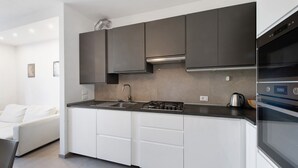 A modern kitchen with white cabinets, a gas stove, and a built-in oven. - Apartment 'Caky's House' with Shared Terrace, Wi-Fi and Air Conditioning (Desenzano del Garda)