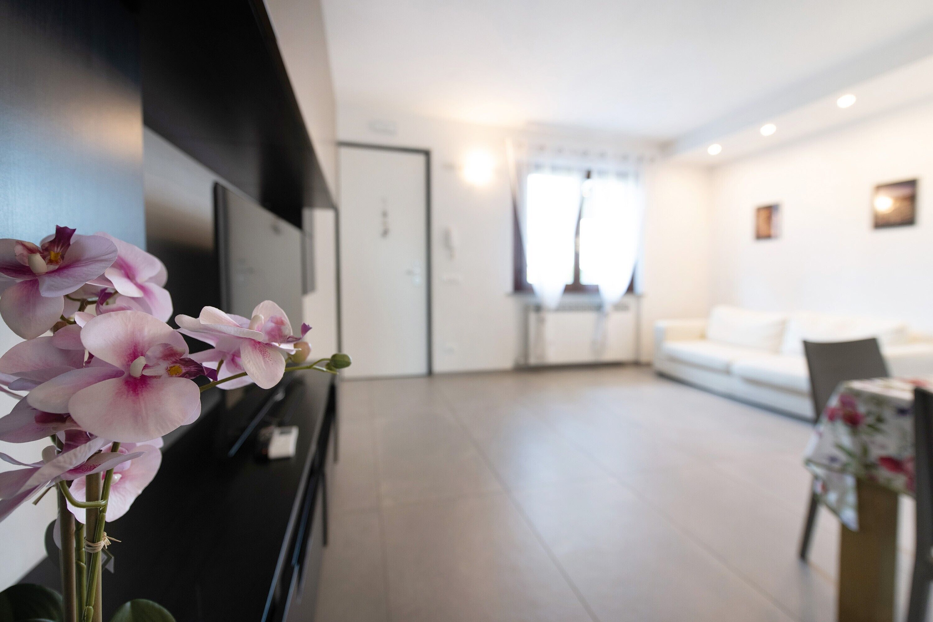 Una sala de estar moderna con un televisor de pantalla plana, un sofá y una mesa con mantel floreado.