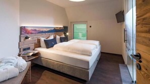 A bedroom with a bed, a nightstand, a painting, and a wooden door. - Exclusive vacation apartments with private spa in the Tyrolean Alps (Zellbergeben)
