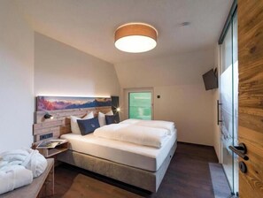 Ein Schlafzimmer mit einem Bett, einem Nachttisch, einem Gemälde und einer Holztür.