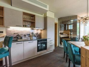 Eine moderne Küche mit eingebauten Geräten, ein Essbereich mit Türkis-Stühlen und ein Holztisch.