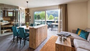 A modern living room with a sofa, coffee table, and dining area with chairs. - Exclusive vacation apartments with private spa in the Tyrolean Alps (Zellbergeben)