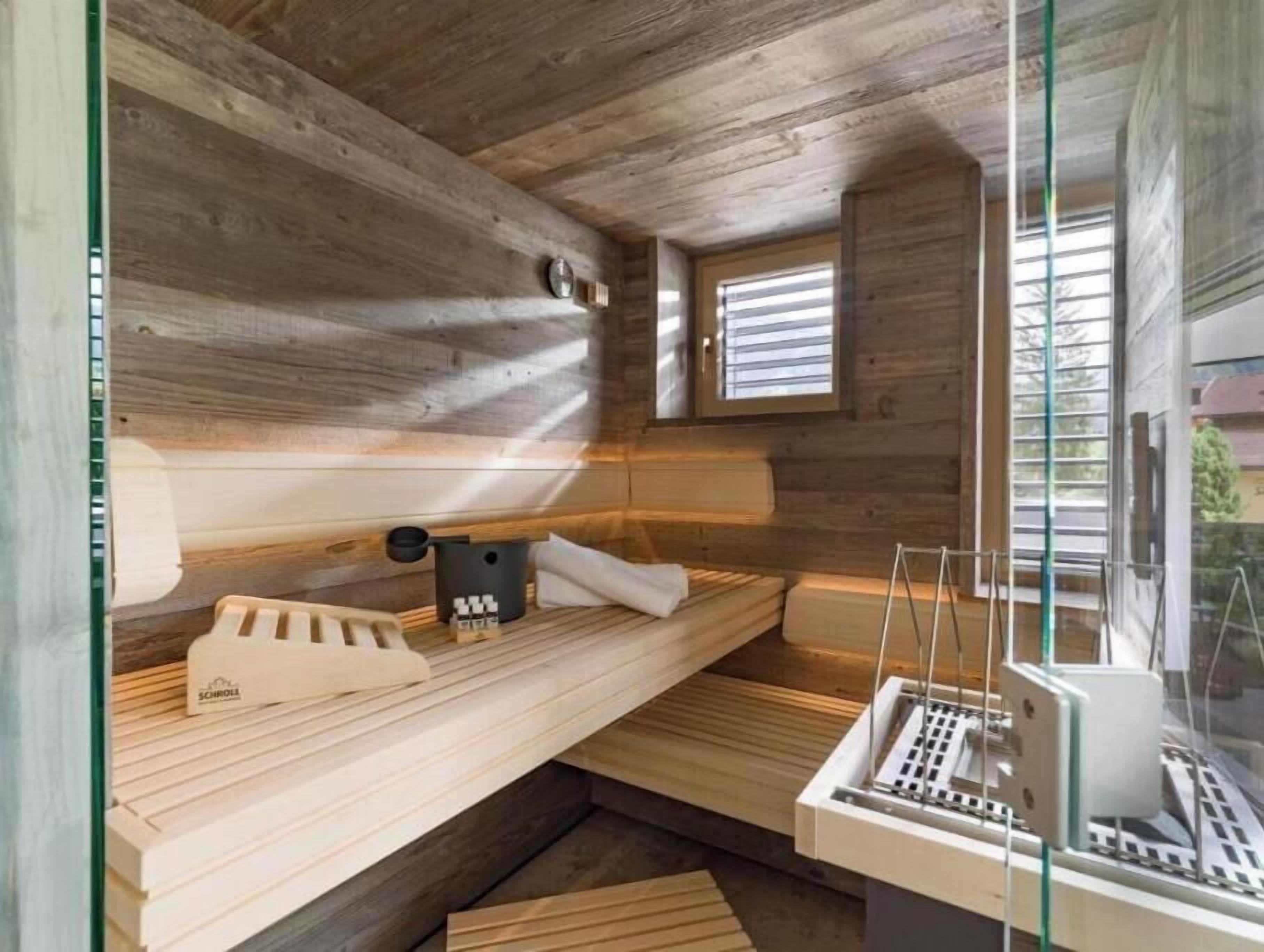 Un cuarto de sauna con paredes de madera, un banco, una toalla y un calentador de sauna.