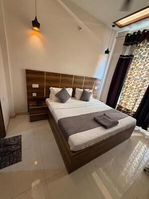 Un dormitorio moderno con cabecera de madera, una cama grande con almohadas, una mesita de noche y una lámpara colgante.