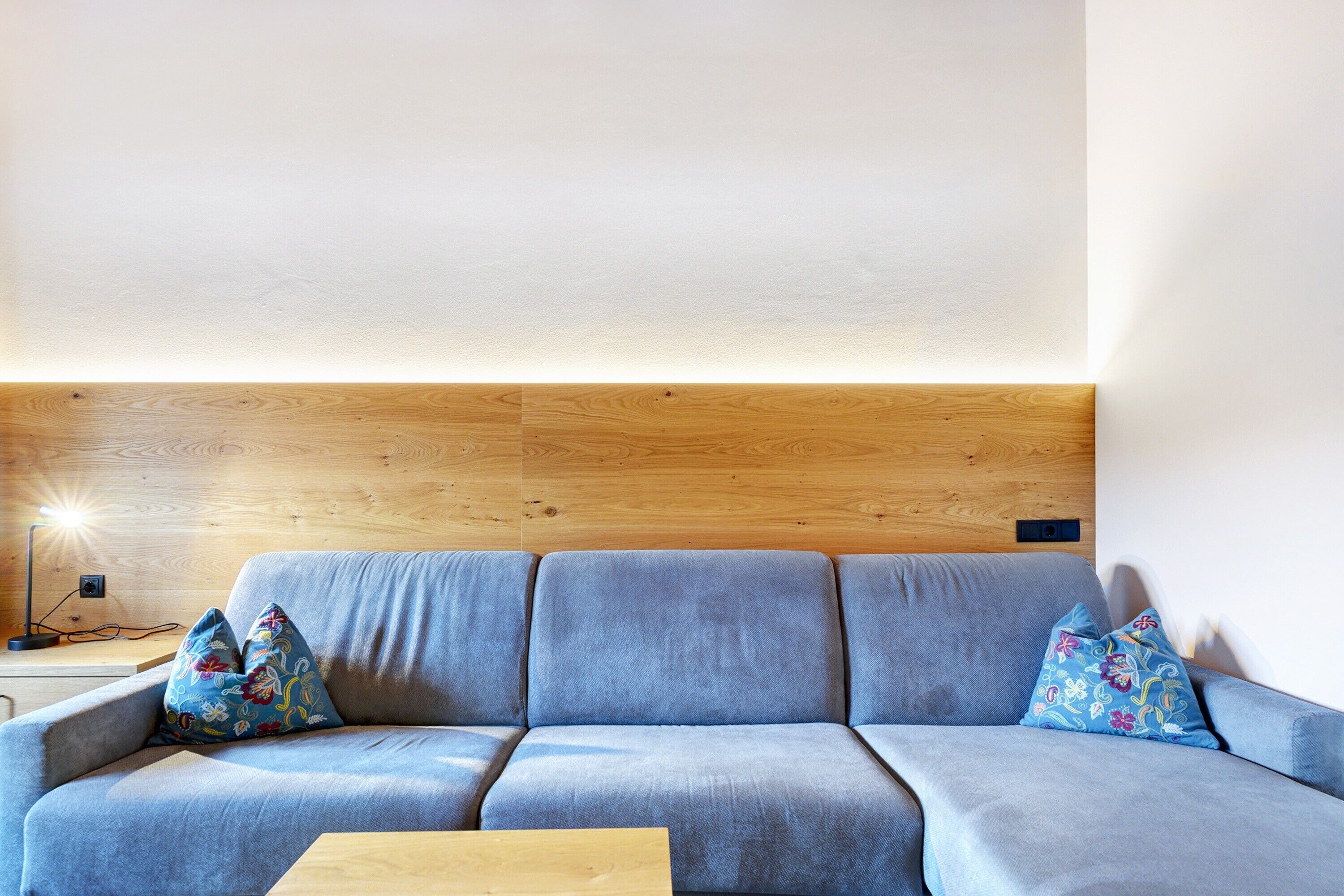 A modern living room with a grey sofa, wooden headboard, and a small wooden coffee table.