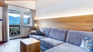 Uma sala de estar moderna com um sofá, uma mesa de centro de madeira e uma vista através de uma porta de vidro.