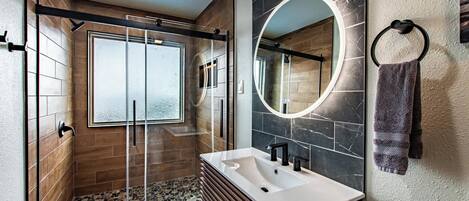 Une salle de bain moderne avec une douche à parois de verre, un meuble-lavabo avec un miroir et un porte-serviettes.
