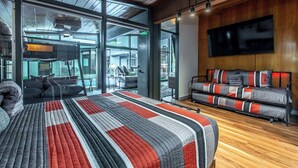 A modern hotel room with a large bed, a sofa, a flat-screen TV, and large windows offering a view of the outdoors. - Luxury on Ocean Drive - Sleeps 28 (Corpus Christi)