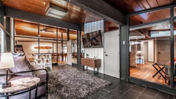 Un salon moderne avec une grande télévision, un canapé, une table basse et un tapis.