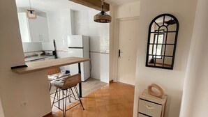 Una cucina con mobili bianchi, un piano di lavoro in legno e un lampadario.