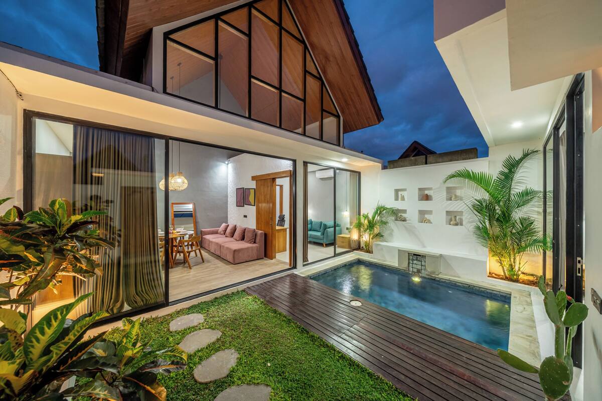 Una casa moderna con piscina, puertas de cristal y zona de patio.