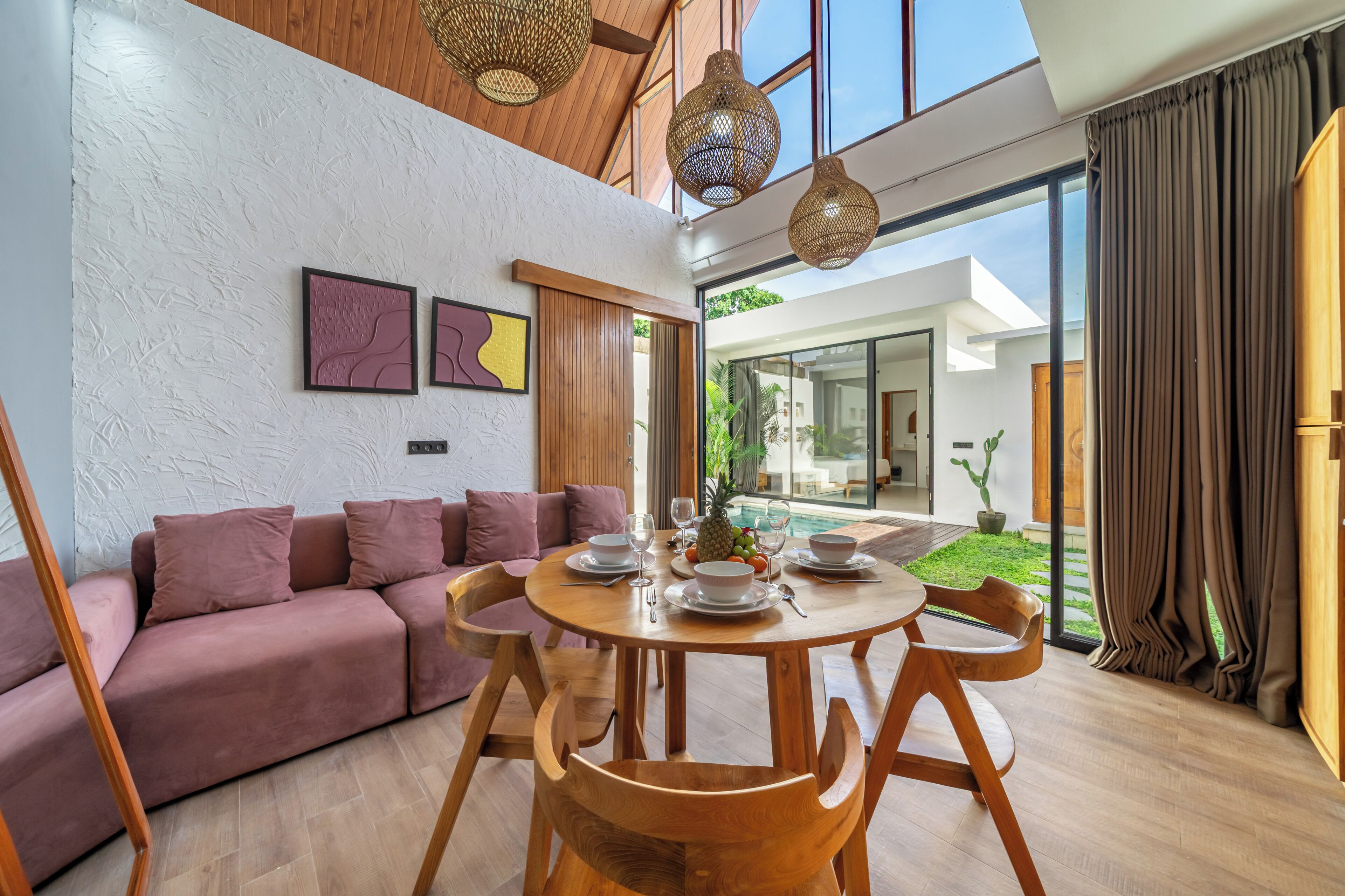 Una sala de estar moderna con una mesa de comedor de madera, asientos acolchados y obras de arte en las paredes.