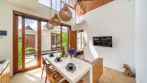 A modern dining area with a large table, wooden chairs, and a ceiling fan. - Harmony Villas  (Denpasar)