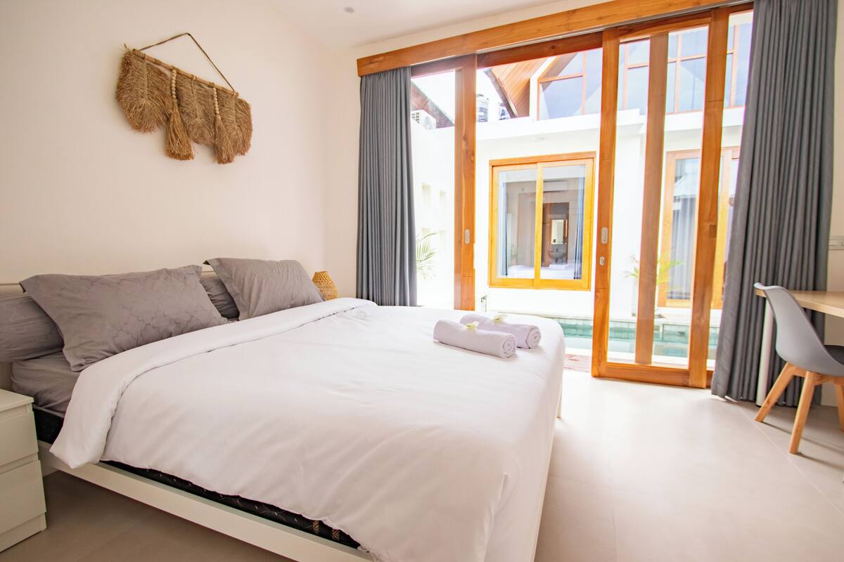 Un dormitorio con cama, escritorio y vistas al exterior.