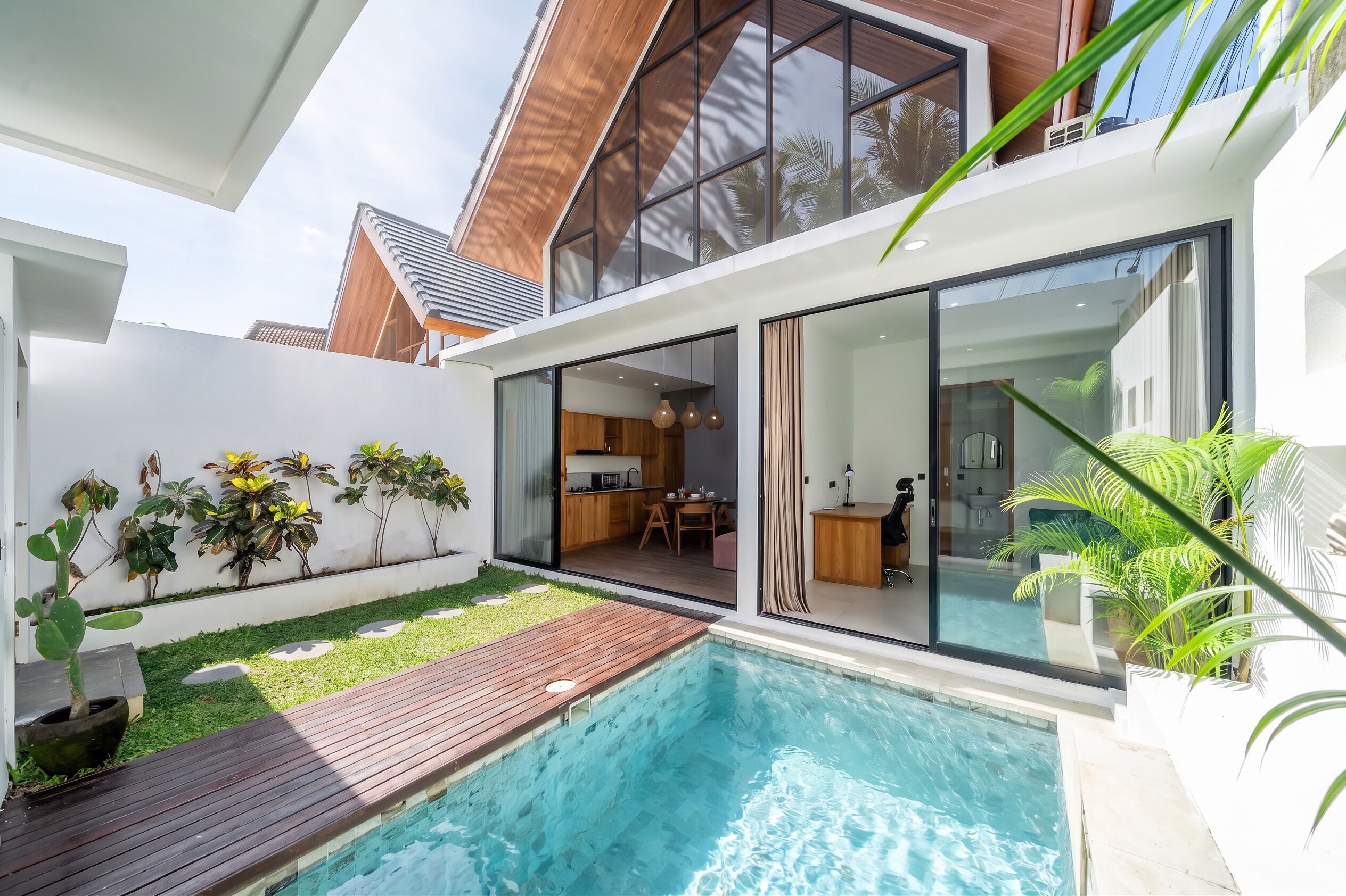 Una casa moderna con piscina, comedor y cocina visibles a través de amplios ventanales.