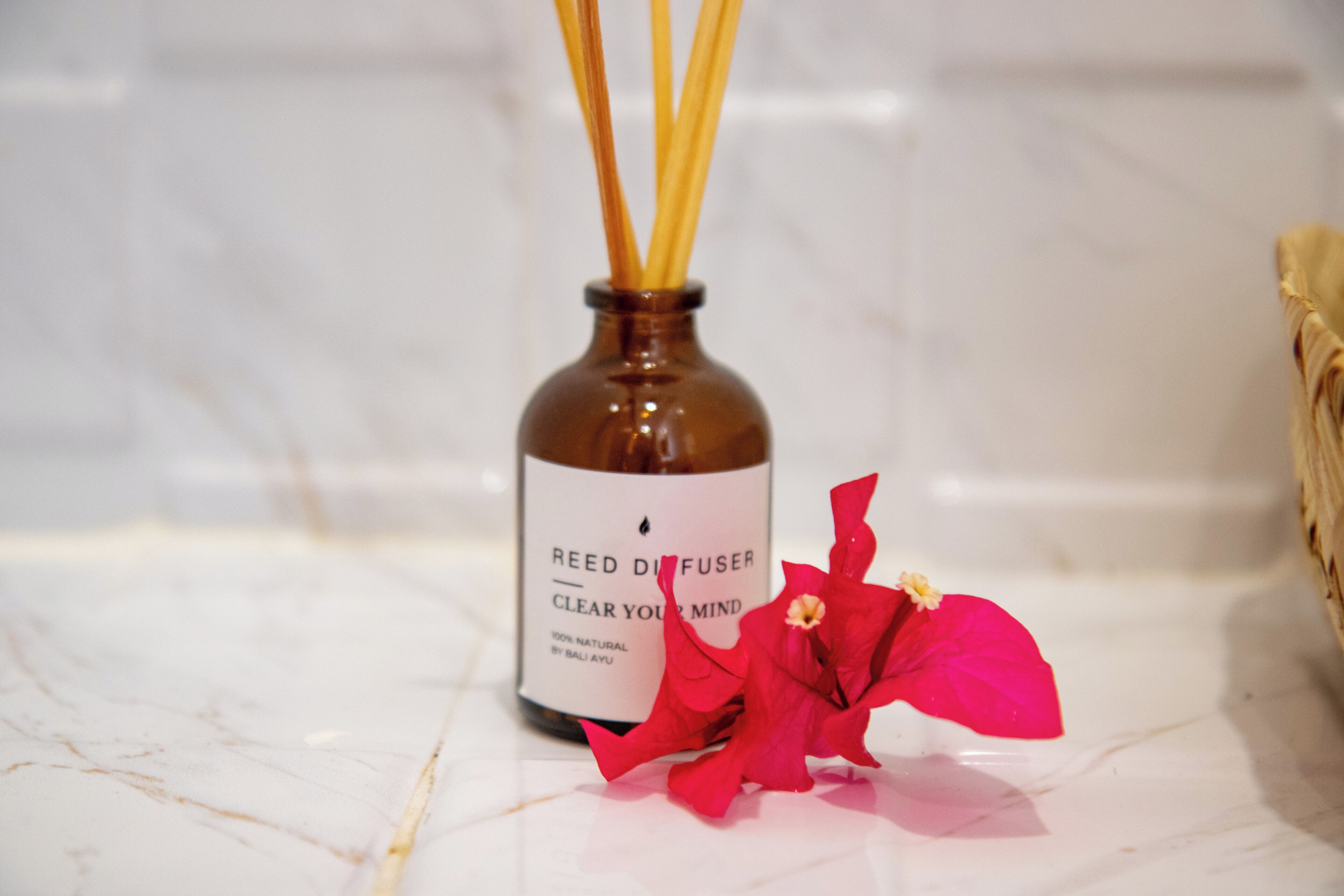A bottle of reed diffuser with a label that reads "Clear Your Mind" and a red flower beside it.