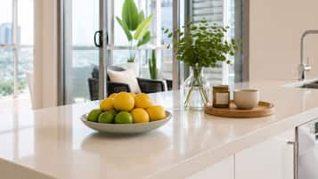 A kitchen counter with a bowl of lemons and limes, a vase with green plants, and a small jar.