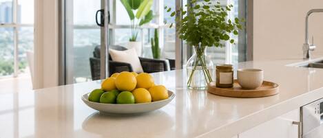 Una encimera de cocina con un cuenco de limones y limas, un florero con plantas verdes y un frasco pequeño.