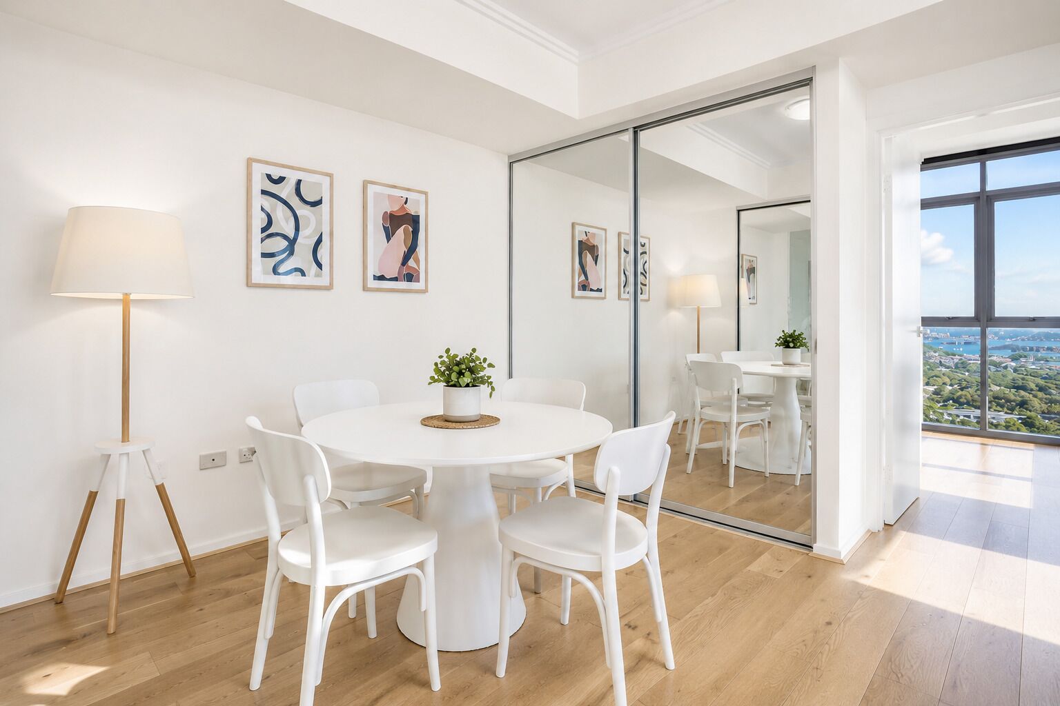A modern interior with a round table, white chairs, a floor lamp, and artwork on the walls.