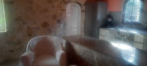 A kitchen with a stone wall, a white door, a refrigerator, and a window. - Traditional Stone House in Kerkira Argyrades (Argyrades Kerkira)