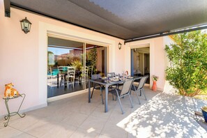 Une terrasse avec une table et des chaises, une statue de tigre décorative et une plante en pot.