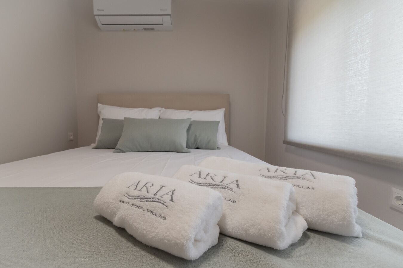Een hotelkamer met een bed, kussens en handdoeken met 'ARIA'-branding.