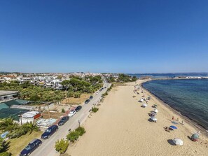 Eine Küstenstraße mit Strand, parkenden Autos und blauem Himmel.
