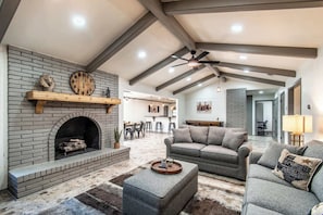 A spacious living area with a fireplace, a sofa, and a dining area in the background. - Ocean Dr Sleeps 19 With Hot Tub & Game Room (Corpus Christi)
