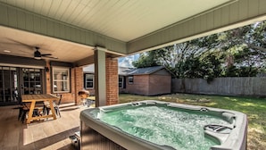 Een achtertuin met een jacuzzi, een houten tafel en stoelen.