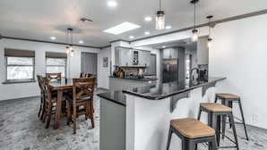 Een moderne keuken met een centraal eiland, barkrukken en hanglampen.