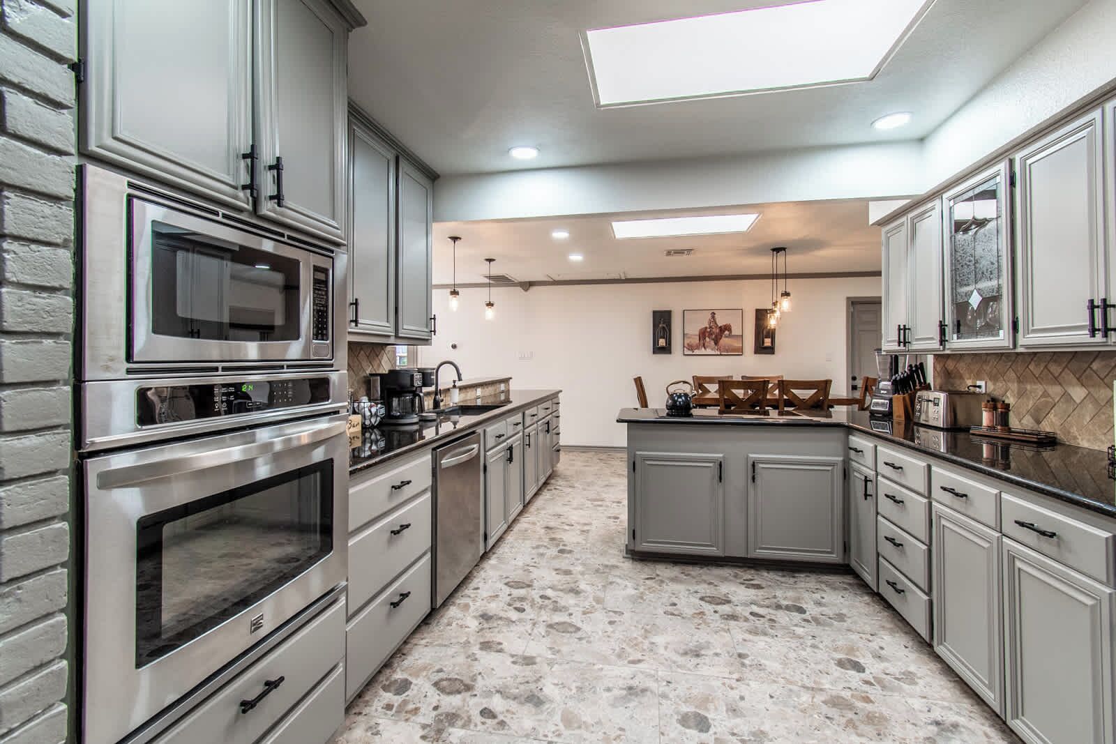 A modern kitchen with stainless steel appliances, grey cabinetry, and a central island.
